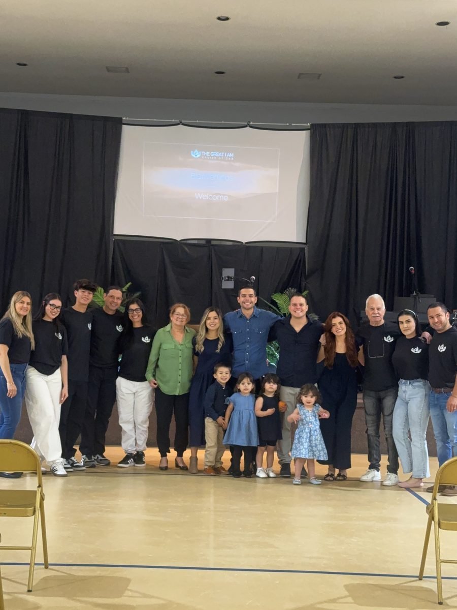 Familias y equipo de servidores de El Gran Yo Soy, adultos y niños, reunidos al frente del salón después de un servicio